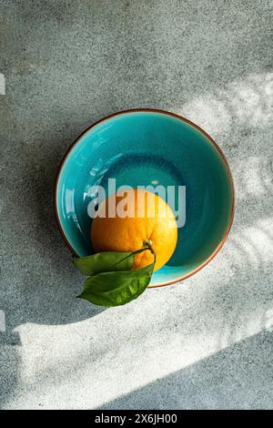 Orange avec des feuilles dans un bol en céramique Banque D'Images