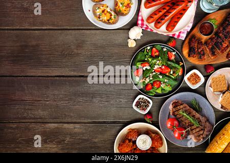 Bordure côté barbecue d'été sur un fond de bois sombre. Variété de viandes grillées, pommes de terre, plats de légumes et smores. Vue de dessus avec espace copie Banque D'Images