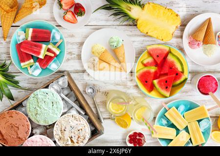 Scène de table rafraîchissante des aliments d'été. Variété de glaces, popsicles et fruits. Vue de dessus sur un fond de bois blanc rustique. Banque D'Images