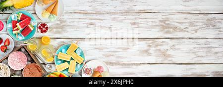 Bordure du coin des aliments d'été rafraîchissants. Sélection de glaces, popsicles et fruits. Vue de haut en bas sur un fond de bannière en bois blanc. Banque D'Images