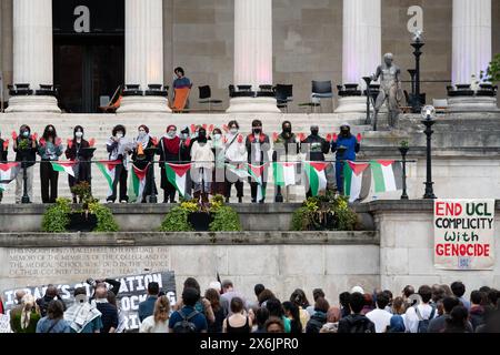 Londres, Royaume-Uni. 15 mai 2024. Des étudiants avec des mains peintes en rouge se tiennent derrière une rangée de drapeaux palestiniens sur les marches de l'University College de Londres alors que 'UCL signifie Justice' rallie dans l'enceinte de l'université, qu'ils occupent depuis le 2 mai 2024, pour protester contre la guerre d'Israël contre Gaza et exiger que le collège se désengage des entreprises, y compris des fabricants d'armes, qui approvisionnent Israël et appeler l'université à condamner les actions israéliennes qui violent le droit international. L'occupation étudiante est l'une des nombreuses qui se déroulent dans le centre de Londres. Crédit : Ron Fassbender/Alamy Live News Banque D'Images