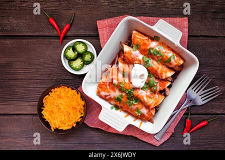 Enchiladas de poulet aux haricots noirs. Plat mexicain. Scène de table vue de dessus sur un fond de bois sombre. Banque D'Images