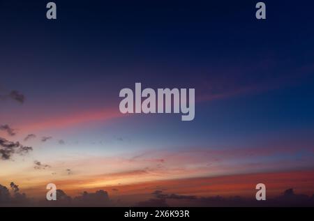 Les nuages colorés sont sous un ciel bleu profond sur un coucher de soleil, photo de fond Banque D'Images