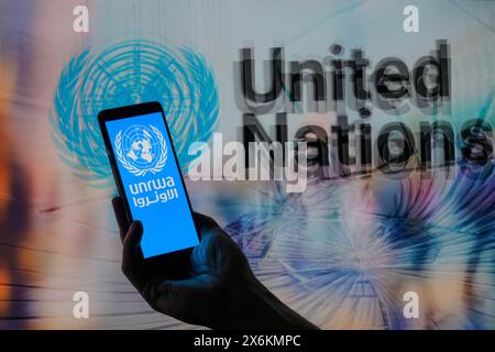 Bruxelles, Belgique. 15 mai 2024. Le logo de l'UNRWA est affiché sur un téléphone intelligent avec l'ONU visible en arrière-plan sur cette illustration photo. Prise à Bruxelles, Belgique. Le 15 mai 2024. (Jonathan Raa/Sipa USA) *** strictement à des fins éditoriales *** crédit : Sipa USA/Alamy Live News Banque D'Images