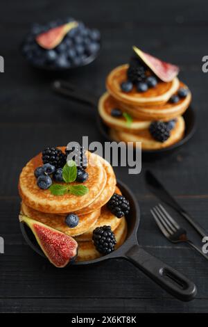 Crêpes dorées sur un fond en bois noir élégant orné de baies juteuses dégageant chaleur et plaisir Banque D'Images