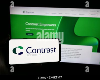 Personne tenant un smartphone avec le logo de la société de logiciels américaine Contrast Security Inc devant le site Web. Concentrez-vous sur l'affichage du téléphone. Banque D'Images