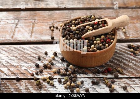 Épice aromatique. Différents poivrons dans un bol et une cuillère sur une table en bois, espace pour le texte Banque D'Images