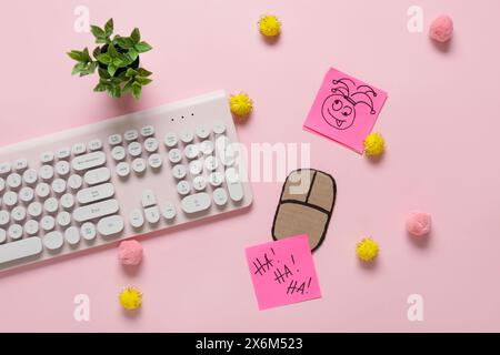 Clavier d'ordinateur avec souris de carton, notes adhésives et décor sur fond rose. Farce du jour des fous d'avril Banque D'Images