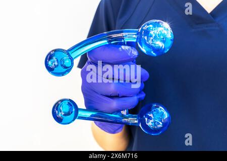 Docteur tient bleu acrylique dos, jambe, outil de massage du cou avec la main gantée. Massage des tissus profonds, masseur de pouce avec boutons pour le point doux, muscles Banque D'Images