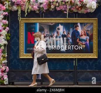 Bucarest, Roumanie. 15 mai 2024 : les gens passent par une publicité de Netflix Bridgerton série TV est affichée sur une station de bus décorée de fleurs dans le centre de Bucarest crédit : Lucian Alecu / Alamy Live News Banque D'Images