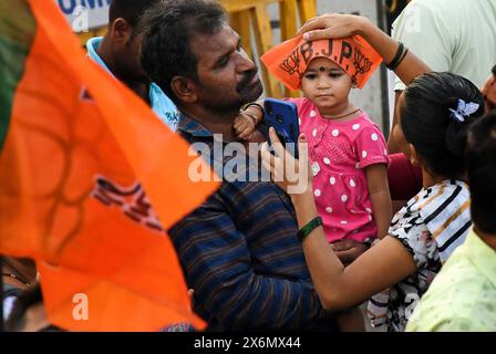 Mumbai, Inde. 15 mai 2024. Une femme met une casquette Bharatiya Janata Party (BJP) sur la tête d'une petite fille avant le Road show à Mumbai. Le premier ministre indien Narendra Modi a organisé une tournée à Ghatkopar (quartier de la banlieue nord-est) à Mumbai pour canaliser le soutien aux candidats du Bharatiya Janata Party (BJP) aux élections de Lok Sabha alors que la ville ira voter le 20 mai 2024. Crédit : SOPA images Limited/Alamy Live News Banque D'Images