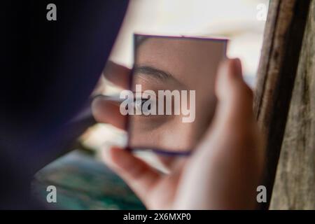 femme asiatique vue d'un petit miroir avec une expression faciale triste. Banque D'Images