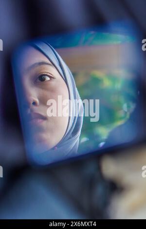 femme asiatique vue d'un petit miroir avec une expression faciale triste. Banque D'Images