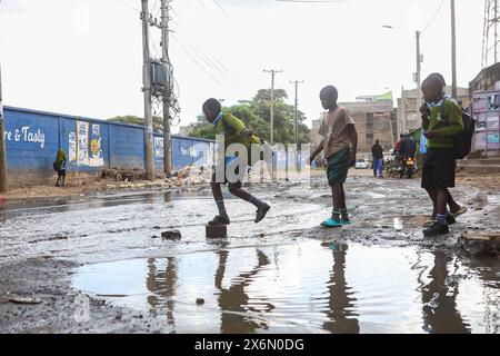 Les écoliers kenyans sautent par-dessus l'eau stagnante près de l'école primaire Mathare Nord à Nairobi qui est près de la rivière Mathare et a été touchée par des inondations déchirantes après que la rivière a éclaté ses berges le 14 mai 2024. Le gouvernement kenyan a ordonné l’évacuation et la démolition de structures et de bâtiments construits illégalement à moins de 30 mètres des rives du fleuve afin d’éviter des pertes en vies humaines à l’avenir. Les agences de sécurité continuent de démolir les maisons construites le long de la rive autour de Nairobi, qui ont été touchées par les inondations qui ont causé des ravages et ont jusqu'à présent tué plus de 200 personnes depuis mars, lorsque la RA a eu lieu Banque D'Images