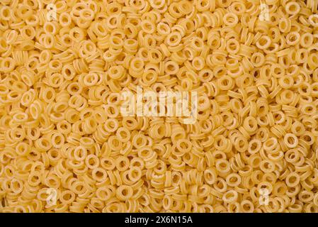 Pâtes anellini crues de blé dur avec du sel et des épices sur un fond de béton foncé Banque D'Images