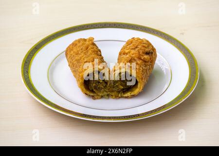 Délicieux rouleau de printemps de poulet coupé en deux sur une assiette sur fond de bois. Banque D'Images