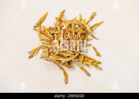 Tas de poissons anchois séchés (Corica soborna) sur fond de bois. Localement au Bangladesh, il est appelé Kachki Shutki. Vue de dessus. Banque D'Images