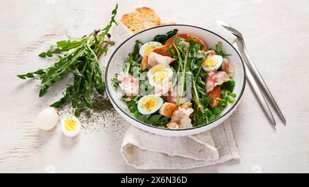 Salade fraîche d'été à partir de feuilles de pissenlit, œufs, bacon et avec du pain sur fond clair. Vue de dessus Banque D'Images