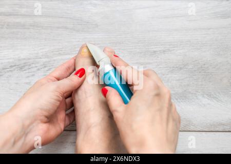 femme ponçant ses ongles d'orteils avec une ponceuse. mycose des ongles. maladie de l'ongle de pied. femme prenant soin des ongles des orteils. ongle jaune. meuleuse d'ongles électrique. entretien f Banque D'Images