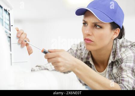 femme ingénieur utilisant un tournevis sur un appareil électrique Banque D'Images