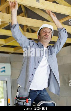 Roofermaker heureux à l'aide d'un marteau dans une construction traditionnelle Banque D'Images