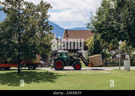 Barwies, Autriche - 15 août 2023 : un tracteur transporte des bottes de foin dans le village autrichien de Barwies Banque D'Images