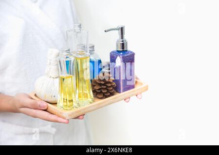 gros plan masseur tenant arôme herbal natural spa set huile crème cire corps peau hydratant plateau de traitement Banque D'Images