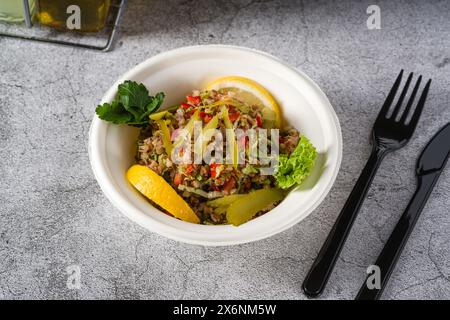 Salade de quinoa sur une assiette blanche en styromousse sur une table en pierre Banque D'Images