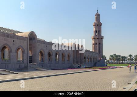 Muscat, Oman - 2 janvier 2024 : les visiteurs explorent les environs sereins de la Grande Mosquée du Sultan Qaboos à Mascate sous un ciel bleu clair. Banque D'Images