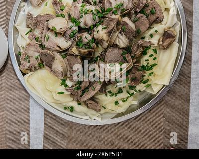 Le plat national kazakh est le beshbarmak. fines tranches de bœuf et d'agneau sur une grande assiette ronde avec de la pâte. Banque D'Images