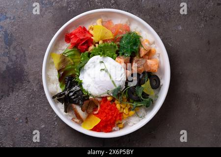 Un bol de poke délicieux et sain rempli d'ingrédients frais comme l'avocat, le concombre, l'edamame, les carottes et le saumon. Banque D'Images