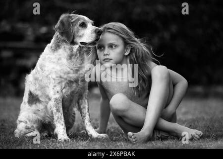 portrait d'une petite fille avec un chien assis une herbe à l'extérieur Banque D'Images