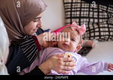 Mère tenant l'enfant regardant la caméra ressentant l'amour avec son bébé portant de beaux vêtements célébrant l'eid Banque D'Images