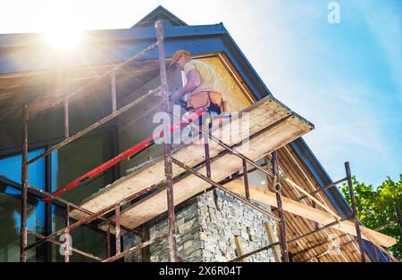 Ouvrier du bâtiment réparant les cheminées d'un bâtiment à l'aide d'échafaudages. Banque D'Images