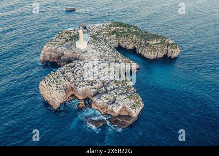 Un petit phare sur un rocher de pierre dans la mer près de la côte Banque D'Images