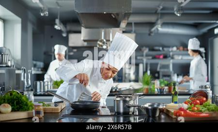 Cuisine du restaurant : Chef femelle noire cuisinant des aliments authentiques délicieux et traditionnels, utilise de l'huile sur la poêle se préparer à frire des patty de viande fermier biologique. Préparation de plats gastronomiques. Grand angle Banque D'Images