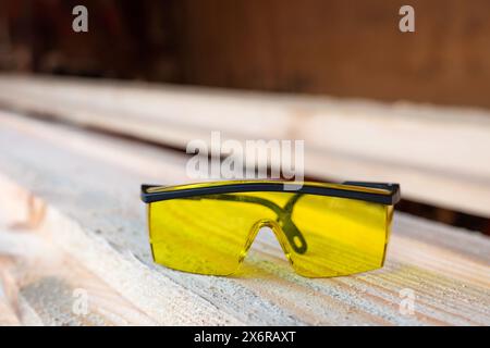 Scierie. Lunettes de sécurité pour la construction sur planches de bois de scierie. Industrie du travail du bois Banque D'Images