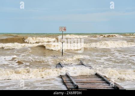 Lido di Jesolo, Italie - 2 mai 2024 : tempête sur la plage de Lido di Jesolo en Italie. Une jetée sur la plage avec de fortes vagues et un panneau d'avertissement disant : pas de saut *** Unwetter am Strand von Lido di Jesolo in Italien. Ein Steg am Strand mit Starken Wellen und ein Warnschild mit Aufschrift : Springen verboten Banque D'Images