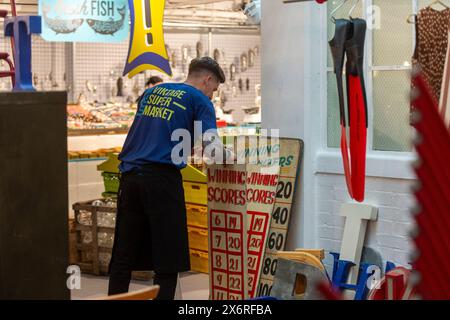 Londres, Royaume-Uni. 16 mai 2024. Un membre du personnel avec des enseignes vintage au supermarché Vintage, un événement pop-up de quatre jours à Soho, par l'équipe de Merchant & Found qui, en tant que «Champions of the Forgotten Maker», ont chargé les principaux fabricants contemporains de créer des œuvres exclusives pour l'événement. Le pop-up fait partie de la London Craft week, un festival organisé dans toute la ville pour célébrer un savoir-faire exceptionnel, dans de multiples secteurs et disciplines. Credit : Stephen Chung / Alamy Live News Banque D'Images