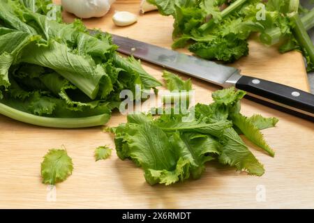 Bouquet fraîchement cueilli de légumes amsoi vert bio sur une planche à découper en gros plan Banque D'Images