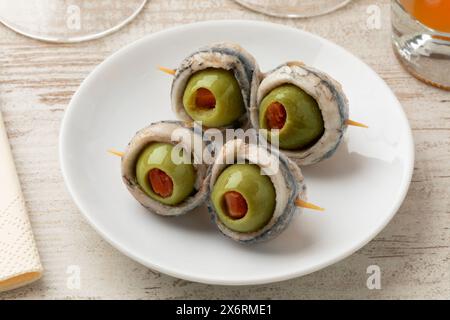 Tapas espagnoles, collez avec une paire d'olives vertes farcies au poivron rouge et à l'anchois sur une assiette de gros plan Banque D'Images