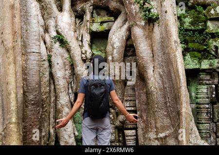 Touriste caucasien méconnaissable devant le Big Trunk et les racines d'un arbre géant à Ta Prohm, Angkor Wat, Siem Reap, Cambodge Banque D'Images