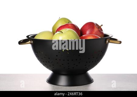 Pommes fraîches en passoire sur table sur fond blanc Banque D'Images