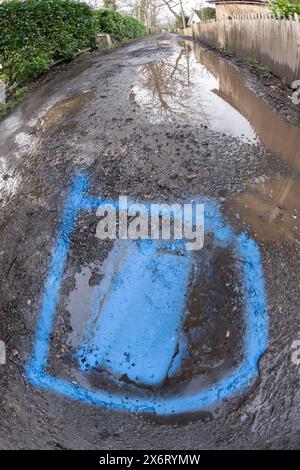 La peinture bleue en aérosol a finalement été utilisée pour identifier une fuite signalée dans l'eau principale seulement 4 semaines plus tard, détruisant la route non adoptée Banque D'Images
