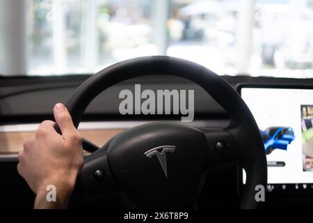 Main masculine sur la colonne du conducteur, derrière le volant Tesla modèle y voiture électrique, voiture de tourisme moderne, présentant des caractéristiques intérieures telles que la roue de contrôle, Banque D'Images