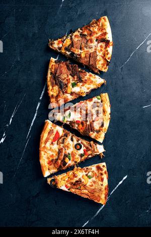 Délicieuse pizza tranchée avec garnitures colorées sur fond foncé Banque D'Images