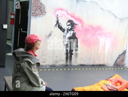 New York, New York, États-Unis. 15 mai 2024. Une femme voit ''˜l'enfant migrant' 2019 Île de Dorsoduro, Venise Italie (série migrant) vu à l'ouverture du nouveau musée Banksy situé au 277 canal Street dans le Lower Manhattan. Plus de 160 œuvres de Banksy ont été recréées par 10 artistes anonymes, car toutes les œuvres sauf une n'existent plus. (Crédit image : © Nancy Kaszerman/ZUMA Press Wire) USAGE ÉDITORIAL SEULEMENT! Non destiné à UN USAGE commercial ! Banque D'Images