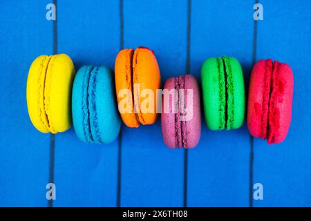 TopShot de macarons français doux et colorés sur fond en bois bleu. Banque D'Images