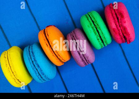 TopShot de macarons français doux et colorés sur fond en bois bleu. Banque D'Images