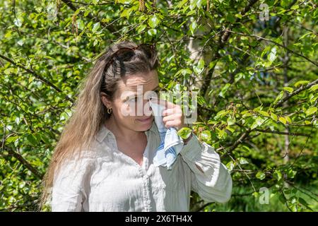 Jeune femme caucasienne, 35 ans, allergique se trouve près du bouleau à fleurs (Betula) à Ystad, Skane, Suède, Scandinavie Banque D'Images